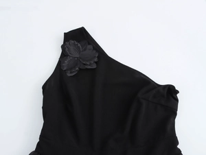 Dettaglio di un elegante abito nero monospalla con una grande decorazione floreale 3D sulla spalla