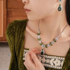 Luxury green zircon leaf necklace and earring jewelry set worn by a model in velvet dress
