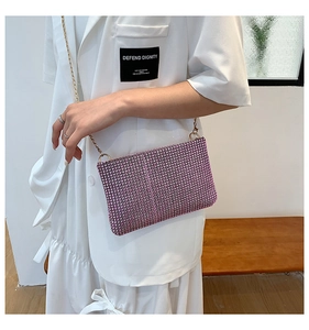 Detail of pink rhinestone chain bag on white dress showing sparkling texture and gold strap