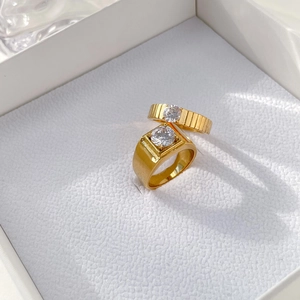 Luxury gold gear-style couple rings with clear gemstones on white gift box lining