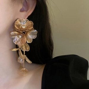 Detail of gold layered flower earrings with metal mesh petals and tassel drop