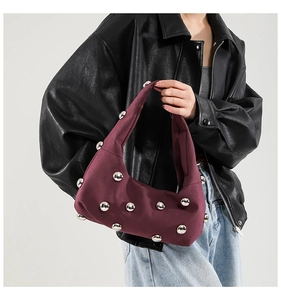 Detail of burgundy canvas shoulder bag featuring decorative silver metal stud rivets