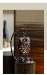 Détail d'un bougeoir chouette en fonte avec bougie chauffe-plat sur socle en bois