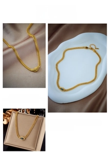 Detail of gold wheat chain necklace featuring a blue evil eye pendant on silk fabric