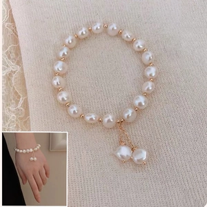 Detailed view of elegant pearl bracelet featuring golden metal spacers and a double pearl drop