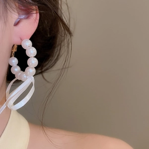 Detailed view of elegant French style pearl hoop earrings featuring a white ribbon bow