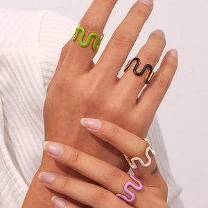 Detail of four colorful enamel wave rings in green, black, white, and purple on a finger