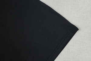 Detailed close-up of double-stitched hem on black knitted dress with sharp fabric texture