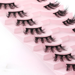 Macro shot of dense black half-false eyelashes arranged on a pink plastic tray