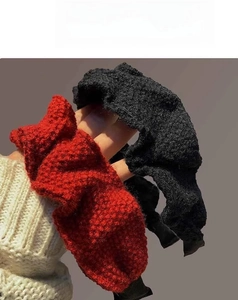 Close-up of red and black knitted headbands showing detailed pleated texture and yarn fabric