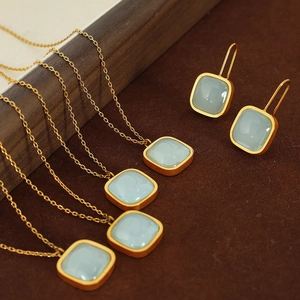 Elegant gold jewelry set featuring light green stone pendant necklace and square earrings
