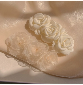 Macro shot of camellia hair clips in satin and organza fabrics with delicate floral texture