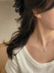 Detail of 925 sterling silver heart necklace with floral relief on elegant model