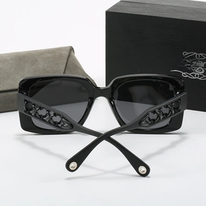 Detail of square black sunglasses with intricate hollow chain temples and gift box