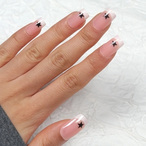 Unghie finte french nude pink con stelle nere e forma quadrata dalla finitura lucida