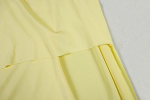 Detail of light yellow ruched fabric showing texture and overlapping layers of the dress