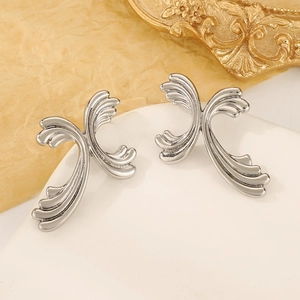 Detailed view of silver comma teardrop earrings on a white stand with gold accents