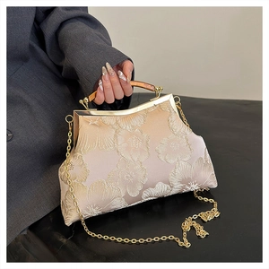 Detail of vintage champagne satin bag featuring intricate 3D floral embroidery and metal frame