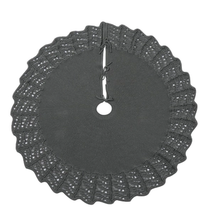 Close-up of dark grey knitted Christmas tree skirt with wavy hollow-out edges and ties