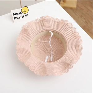 Close-up of pink woven straw sun hat for girls with elastic chin strap and wavy brim