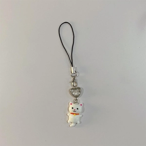 Close-up of a cute white resin kitten charm with an orange collar and silver heart clasp