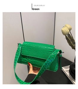 Close-up of green crocodile embossed faux leather baguette bag with a glossy finish