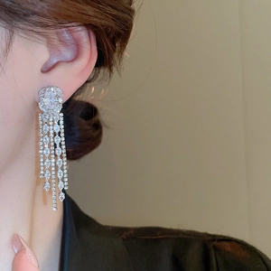 Close-up of elegant silver tassel earrings with sparkling zircon crystals on a model