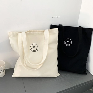 Detail of canvas tote bags in cream and black featuring minimalist smiley face prints