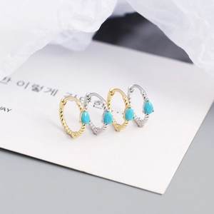 Macro shot of silver and gold rope twist earrings with turquoise stones on card