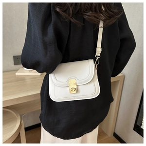 Detail of a cream faux leather crossbody bag featuring a golden rectangular twist lock