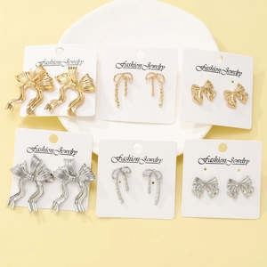 Set of 6 pairs of vintage red bow earrings in gold and silver finishes on display card