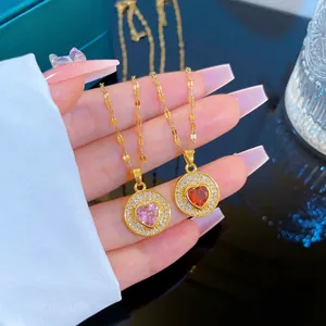 Gros plan de colliers dorés avec pendentifs cœur en zircon rose et rouge sertis de brillants
