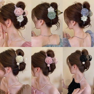 Detail of floral hair claws with mesh and satin texture featuring elegant pearl accents
