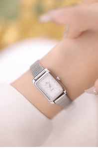 Detail of elegant silver square quartz watch with fine mesh band on a female wrist