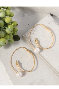 Detail shot of gold S925 sterling silver hoop earrings with white pearls on grey stone