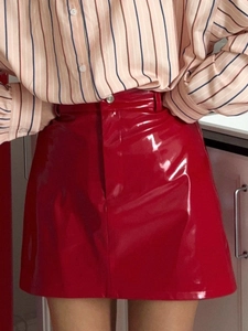 Close-up of a red patent leather mini skirt with a stylish high-waisted fit and glossy finish