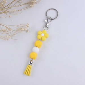 Detail of yellow flower silicone bead keychain with decorative tassel and silver clasp