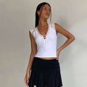 Close-up of white V-neck top with intricate lace trim on the neckline and armholes