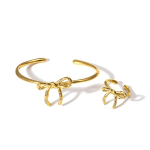 Elegant gold bow jewelry set with sparkling crystals including open ring and bracelet