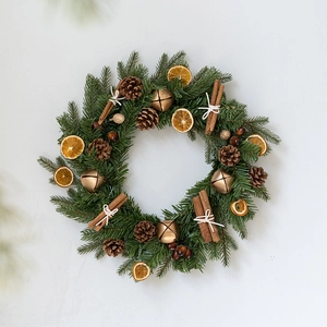 Christmas wreath with green pine needles, pine cones, cinnamon sticks, and gold bells