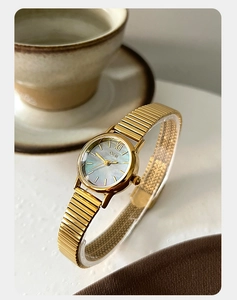 Detail of GEDI gold watch featuring iridescent mother-of-pearl dial and stretch strap