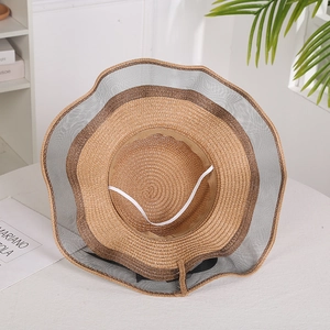 Detail of wide brim straw sun hat featuring mesh splicing and black ribbon bow decoration