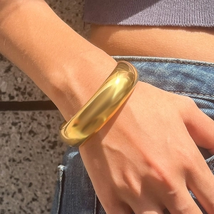 Poliertes 18K vergoldetes Edelstahl-Armband breit am Model bei Sonnenlicht gezeigt