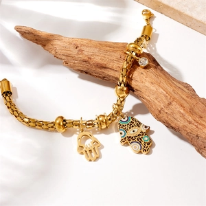 Vintage gold plated Hamsa Hand and Evil Eye charm bracelet on a stylized wood branch