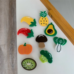 Flat lay of nine colorful acetate fruit and vegetable hair clips on a white background