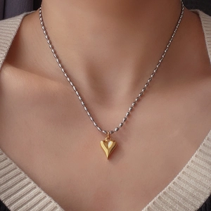 Gros plan du pendentif cœur bicolore poli doré avec sa chaîne à billes argentée