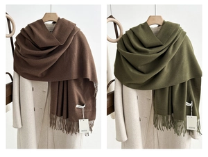 Detailed view of cashmere feel scarf tassels and tags in brown and olive green