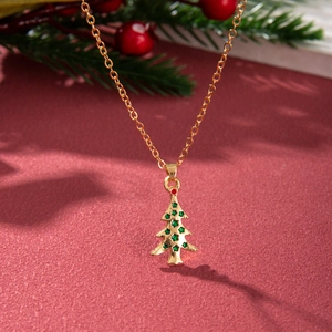 Close-up of golden Christmas tree necklace with green star inlay on red festive background