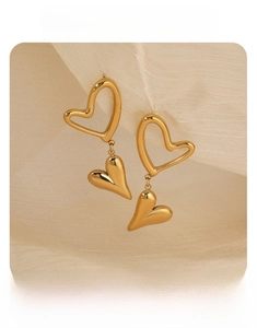 Detail of elegant gold-toned double heart dangle earrings on soft beige fabric