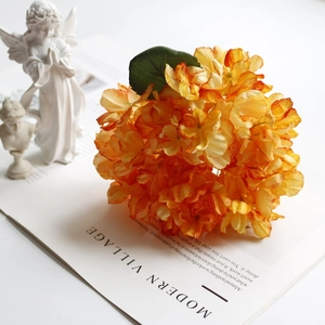 Artistic close-up of vintage orange silk hydrangea on a book with white sculptures